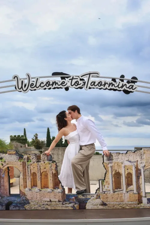 016-couple-smiling-under-welcome-to-taormina-sign