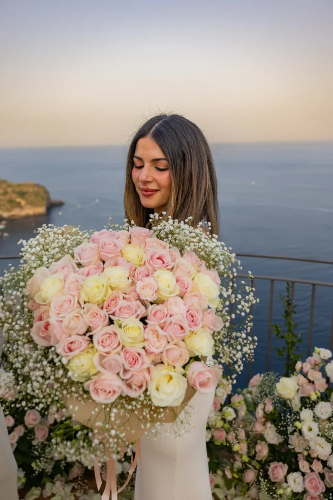 Bride-to-be holding a bouquet of pink and white roses on La Rotonda sul mare, Taormina